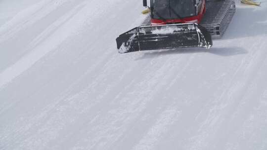 晴天雪地机器在雪坡上移动