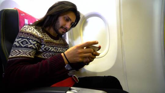 男人坐在飞机上玩手机