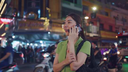 亚洲有魅力的女背包客在城市散步时打电话。