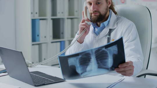 医生一边打电话一边看胸部x光片
