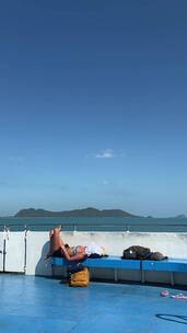 竖屏拍摄妇女在旅行时躺在船上的长椅上