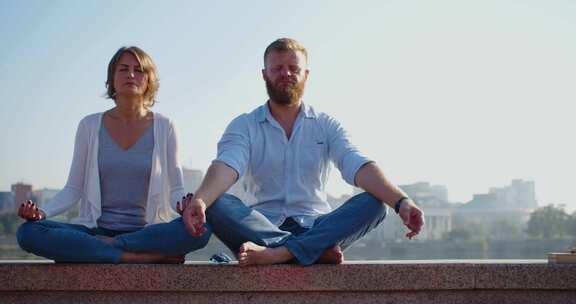 多莉拍摄的一对中年夫妇在城市天际线背景下的屋顶上冥想