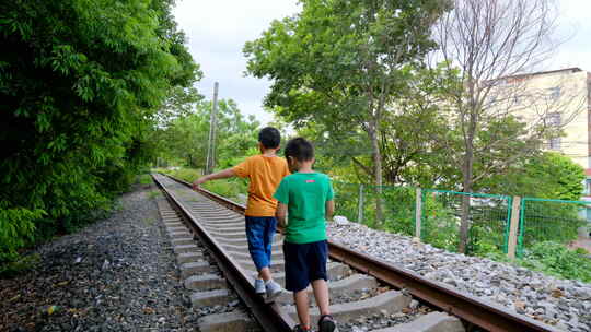 两个小孩走在铁路上玩耍