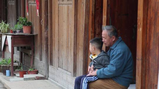 祖孙俩坐在中式房子门前
