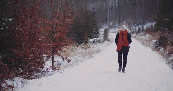 女人走在森林里的雪道上