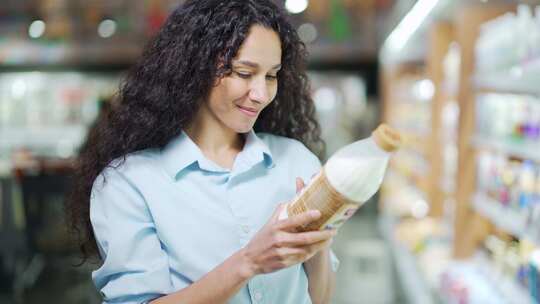 西班牙裔妇女手里拿着一瓶牛奶选择乳制品。视频素材模板下载