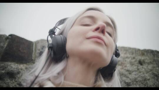 女士戴着耳机在山林里听音乐