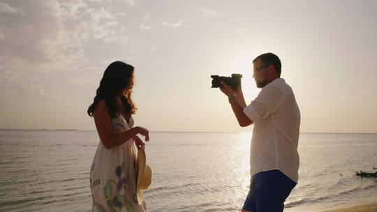 丈夫在海滩上给妻子拍照片