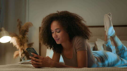 非裔美国人女性20多岁女孩卷发滚动手机晚视频素材模板下载