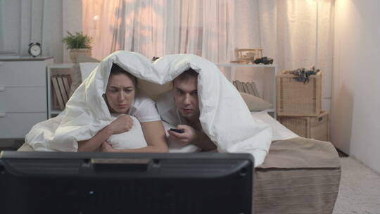 一对情侣坐在床上看恐怖电影视频素材模板下载