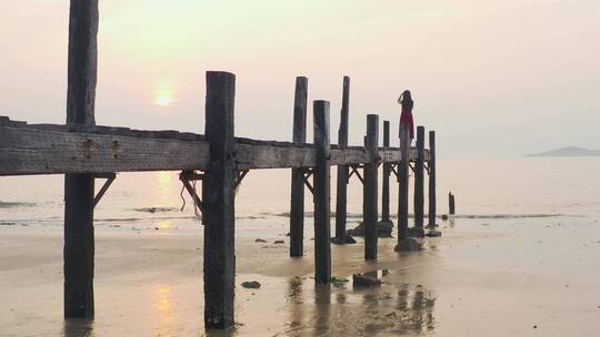 大海边站在木桥看日出的女孩，海水激起浪花