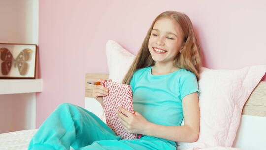 女生拿着书坐在床上微笑视频素材模板下载