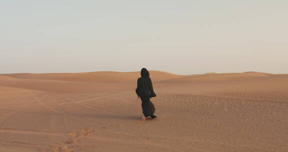 妇女赤脚在沙漠中行走的背影
