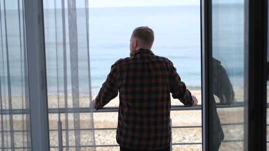 一个男人站在阳台上看着大海