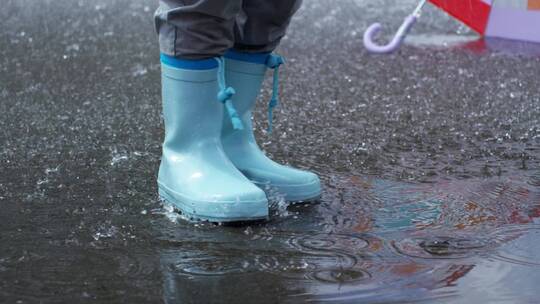 儿童穿靴子在雨中踩踏