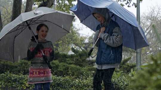 下雨时，女孩和男孩在水坑里跳跃