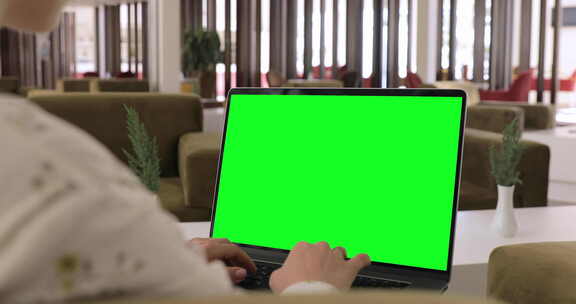 数字游牧女孩远程在豪华酒店休息室用绿屏笔记本电脑工作。