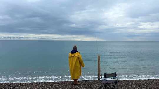 穿着黄色雨衣在海边钓鱼的人
