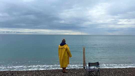 穿着黄色雨衣在海边钓鱼的人视频素材模板下载