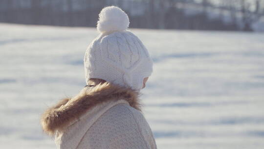 女孩微笑着拉着雪橇走在雪地里