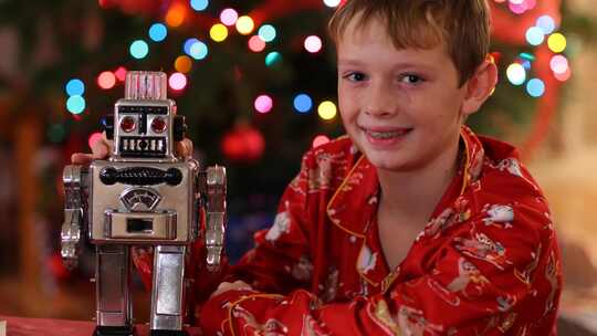 男孩拿着玩具机器人，直视镜头微笑