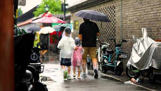 父母牵手孩子雨中漫步空镜实拍