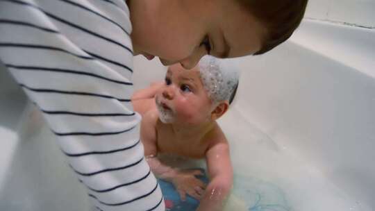 蹒跚学步的孩子在泡沫浴时娱乐婴儿。兄弟姐