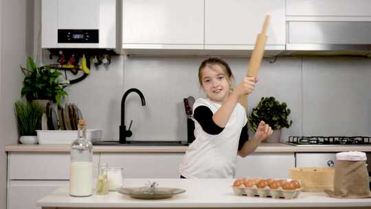 微笑开朗的小女孩在舒适的厨房里手拿别针跳