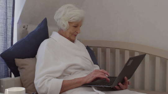 美丽的老太太在酒店用笔记本电脑在线聊天
