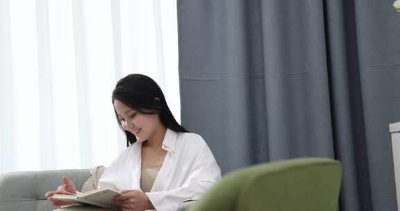 一位年轻女士在家喝咖啡看书