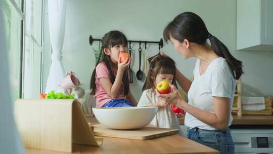 爱美丽的父母妈妈和小兄弟姐妹可爱的女孩孩子感到快乐享受在厨房吃苹果