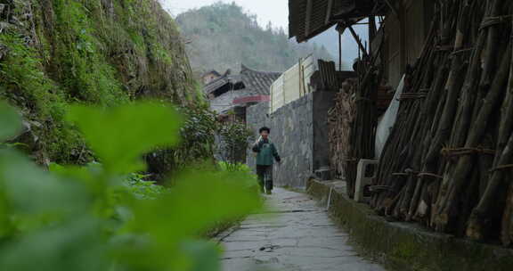 老人背着锄头走在街道