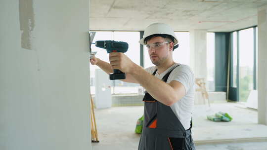 建筑工人在建筑工地用电动工具钻孔墙