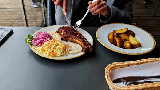 餐厅餐，户外餐桌上有烤排骨、土豆楔子和凉