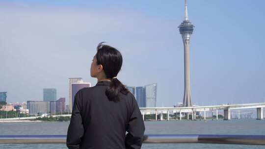 游客站在海岸边看澳门城市风景观望澳门塔