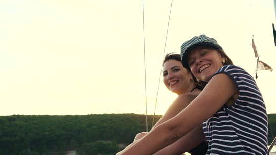 快乐的年轻女性享受日落时河上的帆船之旅