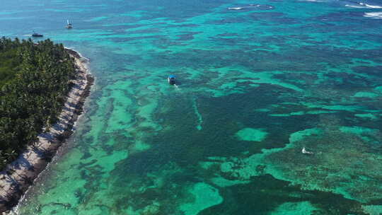 热带海滩上的无人机鸟瞰，棕榈树和快艇在加勒比海航行