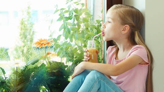 女孩坐在窗台上喝果汁