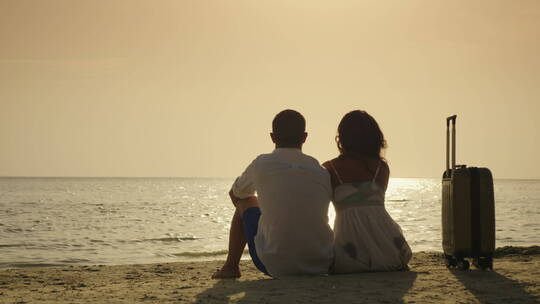 年轻夫妇坐在海边的背影