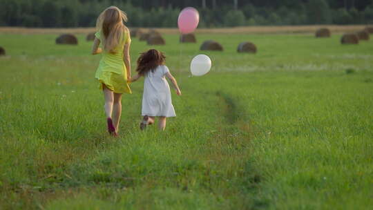 姐妹草地上奔跑手拿气球