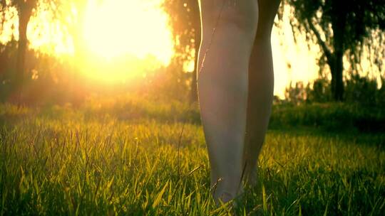 美女光脚迎着日光漫步在草地上