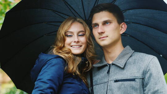 年轻夫妻站在雨伞下谈笑