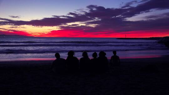 黄昏时分孩子们坐在海滩边的剪影视频素材模板下载