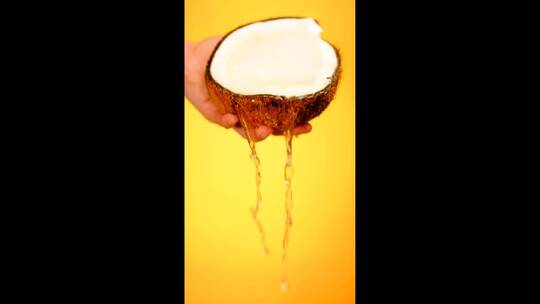 椰子里的水洒在黄色背景上