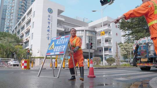 深圳天健小学门口环卫工放置警示牌冲洗地面