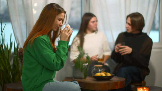 美丽的年轻女子正在聊天夫妇的背景下喝茶。