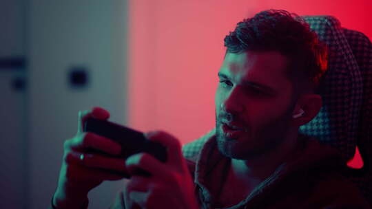 上瘾的游戏玩家通过智能手机玩带有视频游戏的新应用程序情感男人的肖像