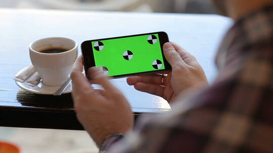 男子在咖啡馆滑动绿幕手机的特写