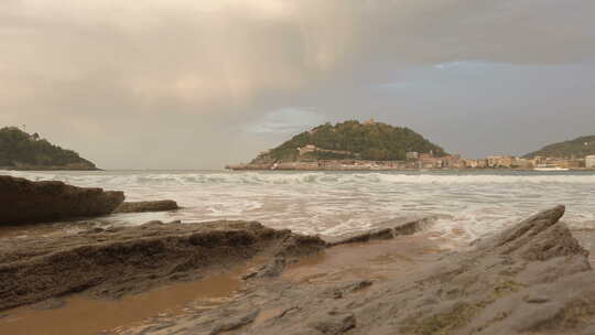 西班牙圣塞巴斯蒂安比斯开多诺斯蒂亚的日落。海滩、岩石、沙子和金色的云视频素材模板下载