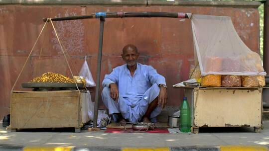 坐在印度街食品摊位的老人视频素材模板下载